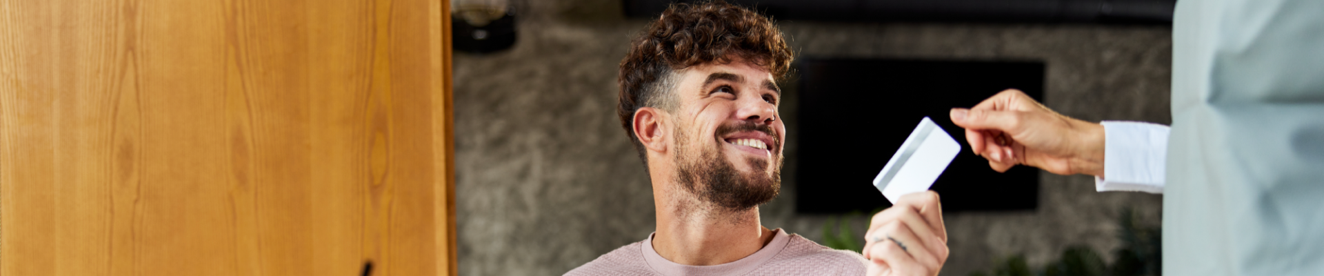 Happy man paying a café bill with a credit card, highlighting ease and convenience in everyday spending.