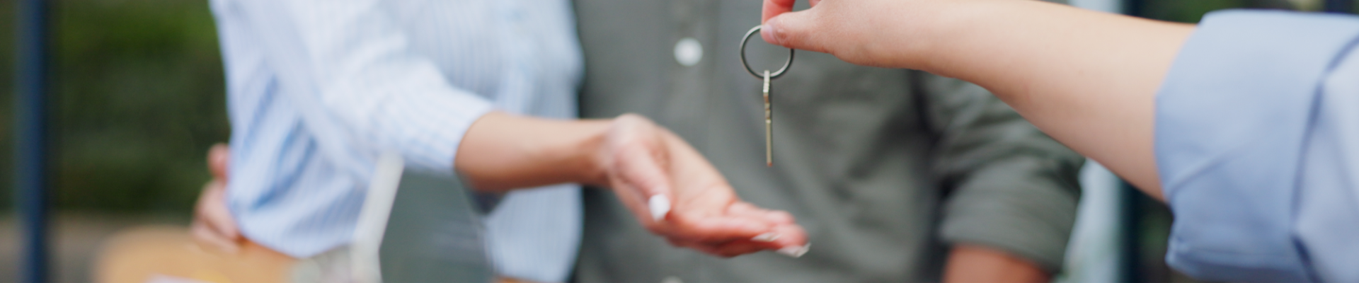 Real estate agent handing keys to a couple, symbolizing successful homebuying and new beginnings.