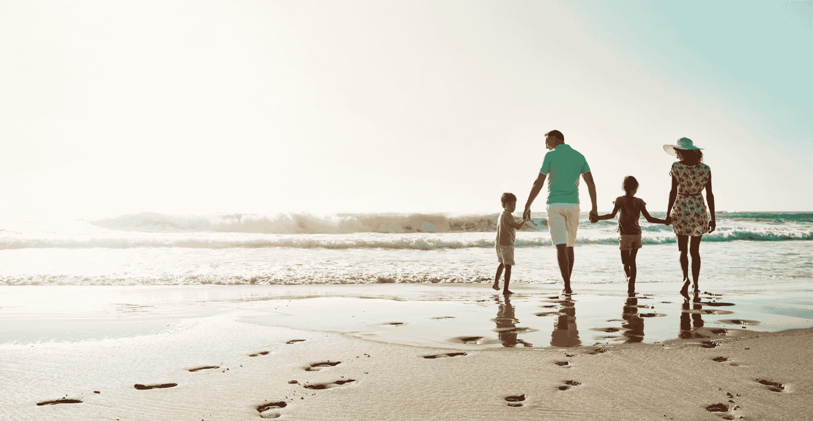 Happy family walking hand in hand on the beach, reflecting togetherness and financial peace of mind.