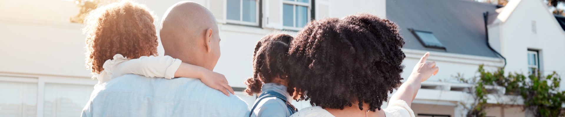 Happy family outside their new home, symbolizing homeownership and new beginnings.