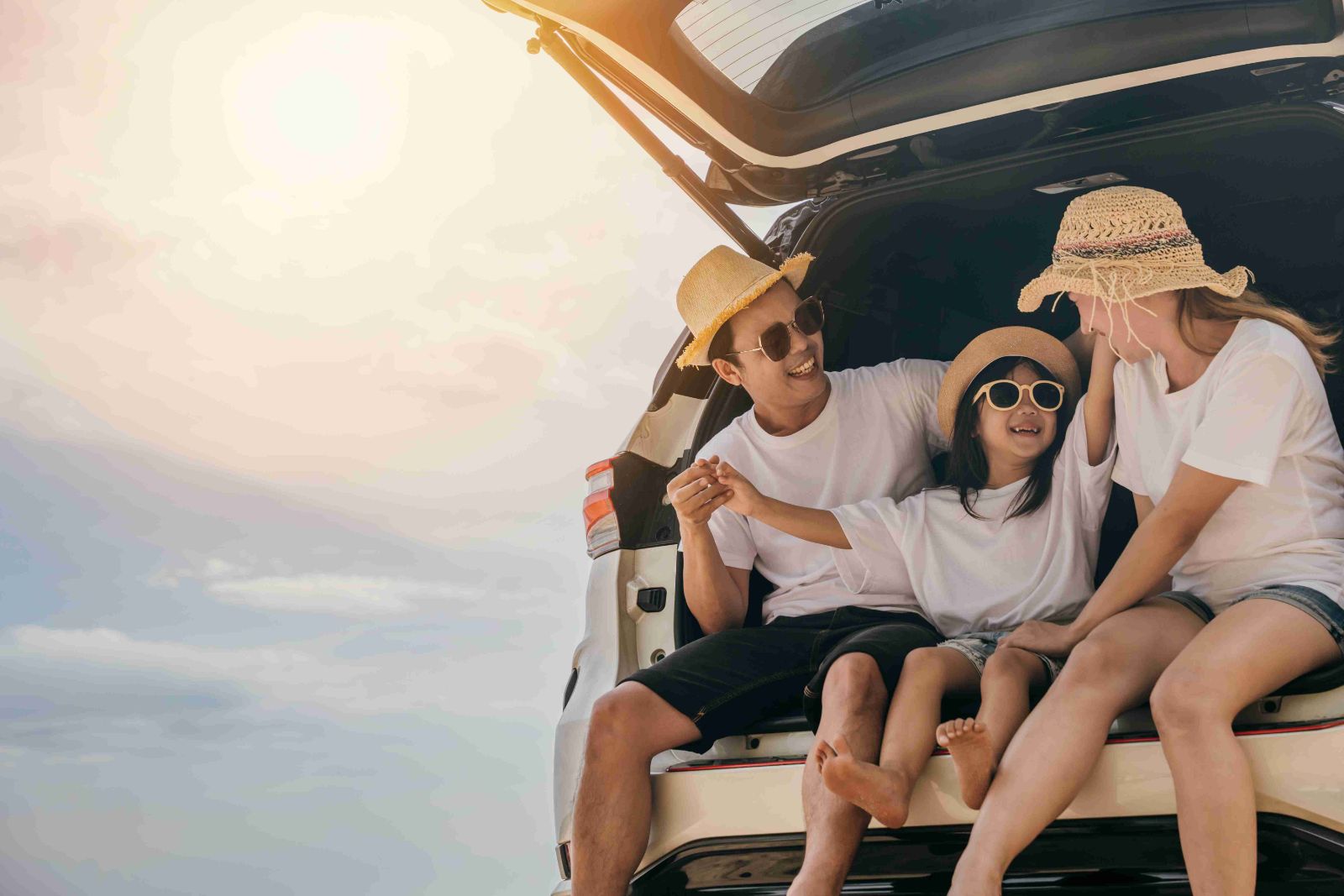 Family sitting on the back of the car at the beach